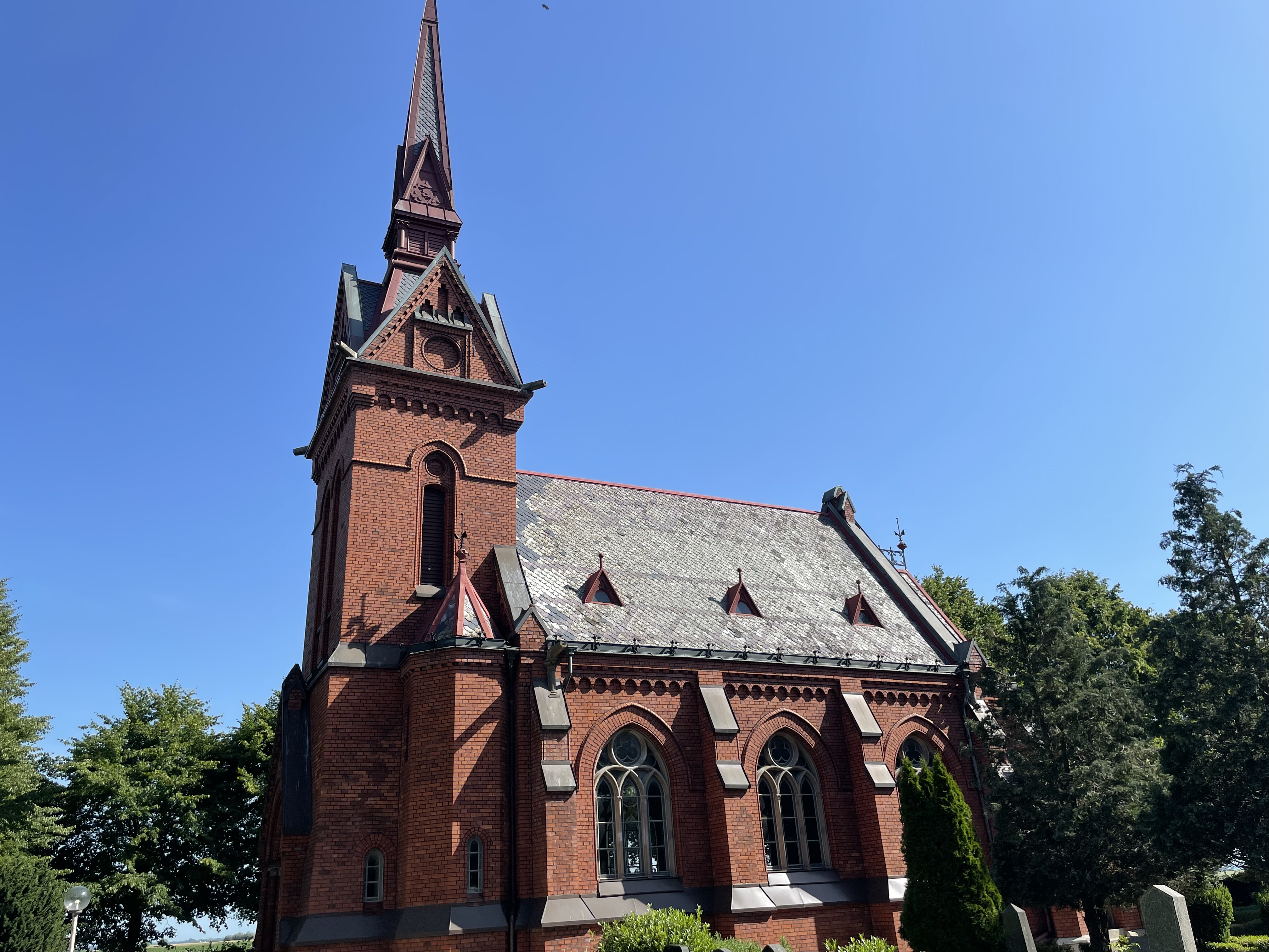 Liten tegelkyrka med högt torn.