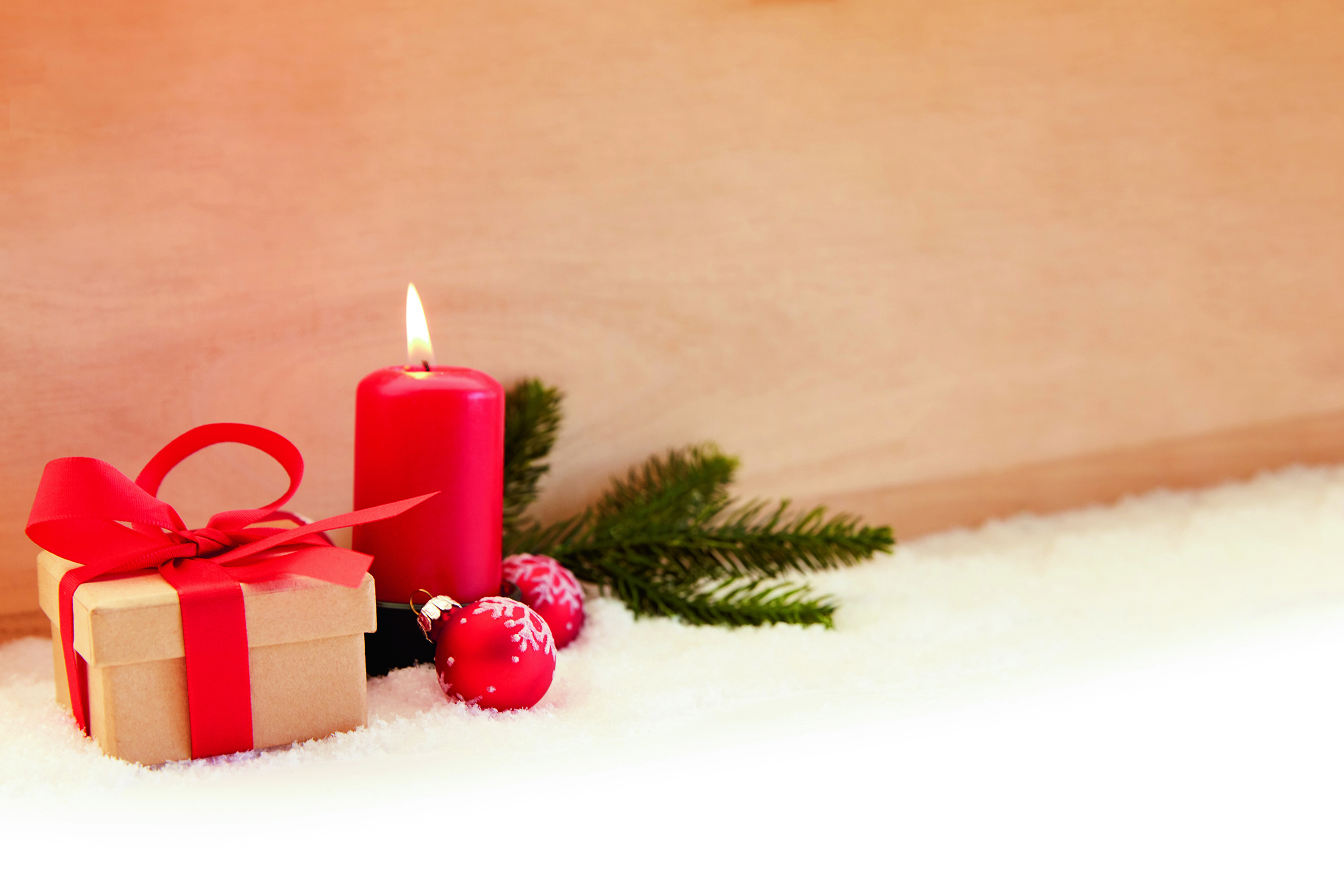 Ett litet paket, ett tänt ljus och en grankvist som skapar julkänsla.