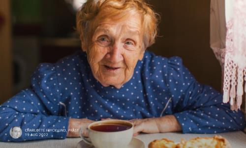 En äldre kvinna sitter vid kaffebordet.