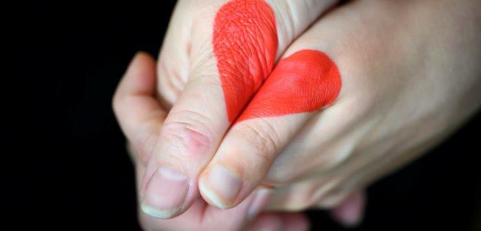 Två knäppta händer med ett rött hjärta målat på dem..