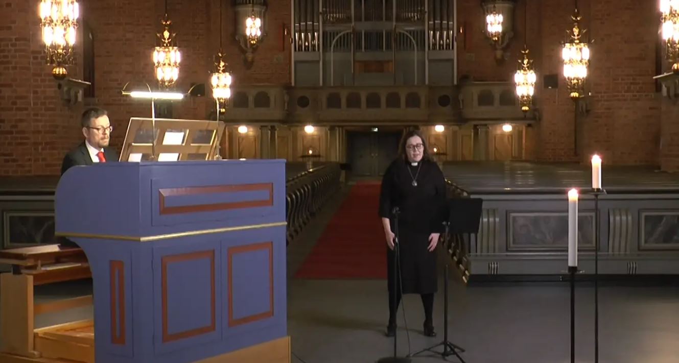 En kvinna sjunger i en kyrka och ackompanjeras av en man som spelar orgel.