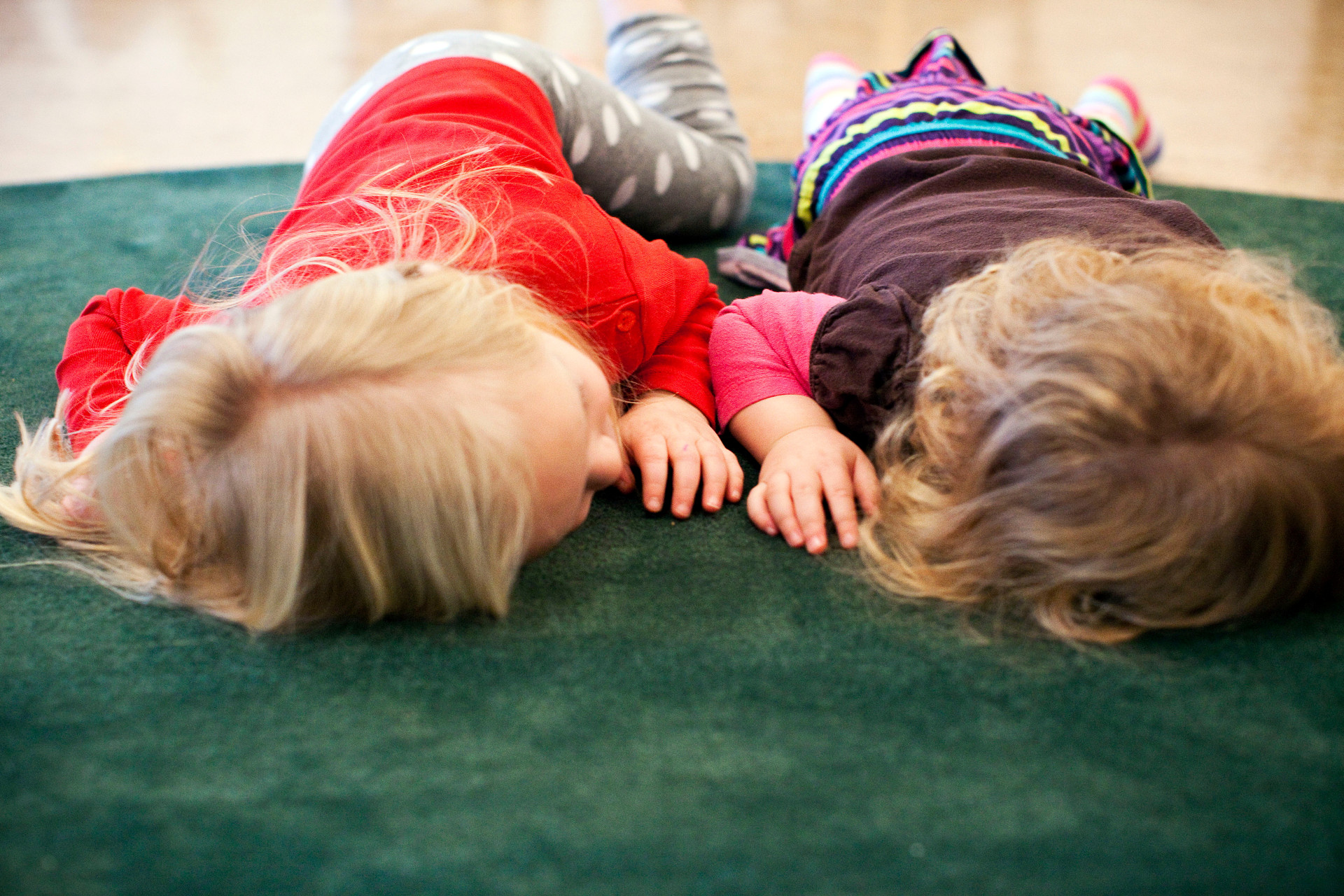 Två barn ligger på mage på en matta.