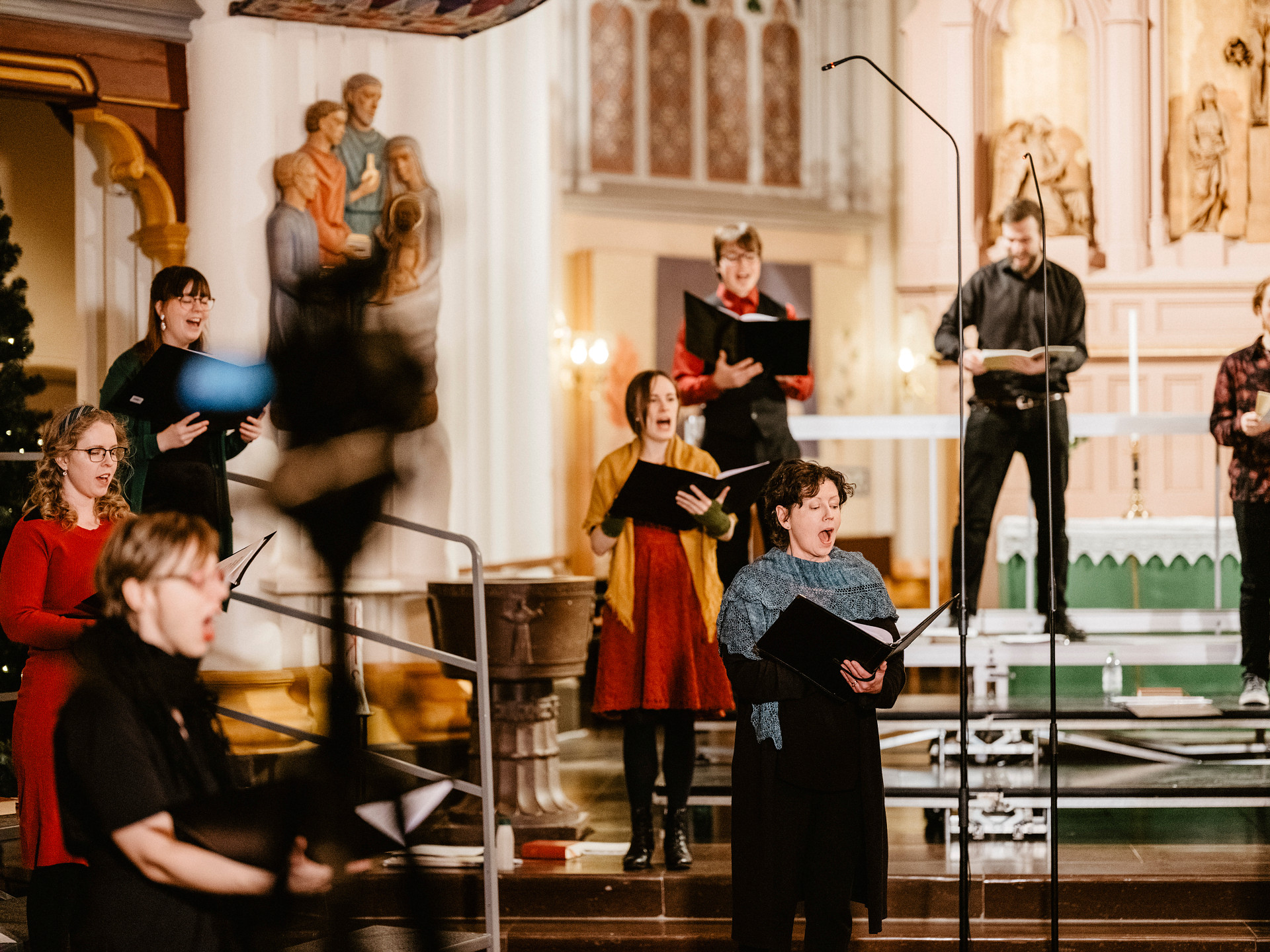 Åtta körsångare står och sjunger på coronasäkert avstånd från varandra i Umeå stads kyrka.