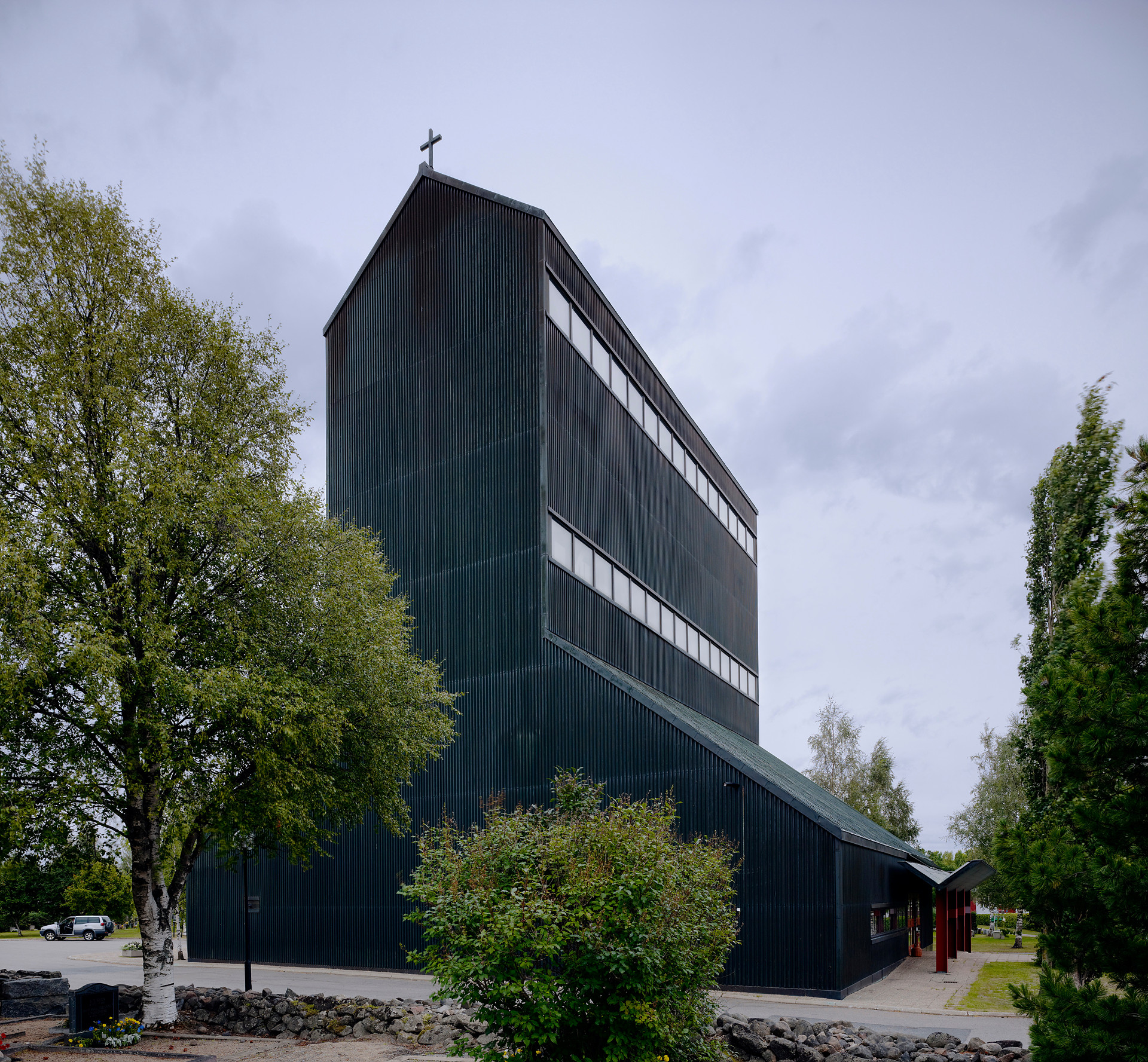 Tummaksi maalattu kirkko puiden keskellä