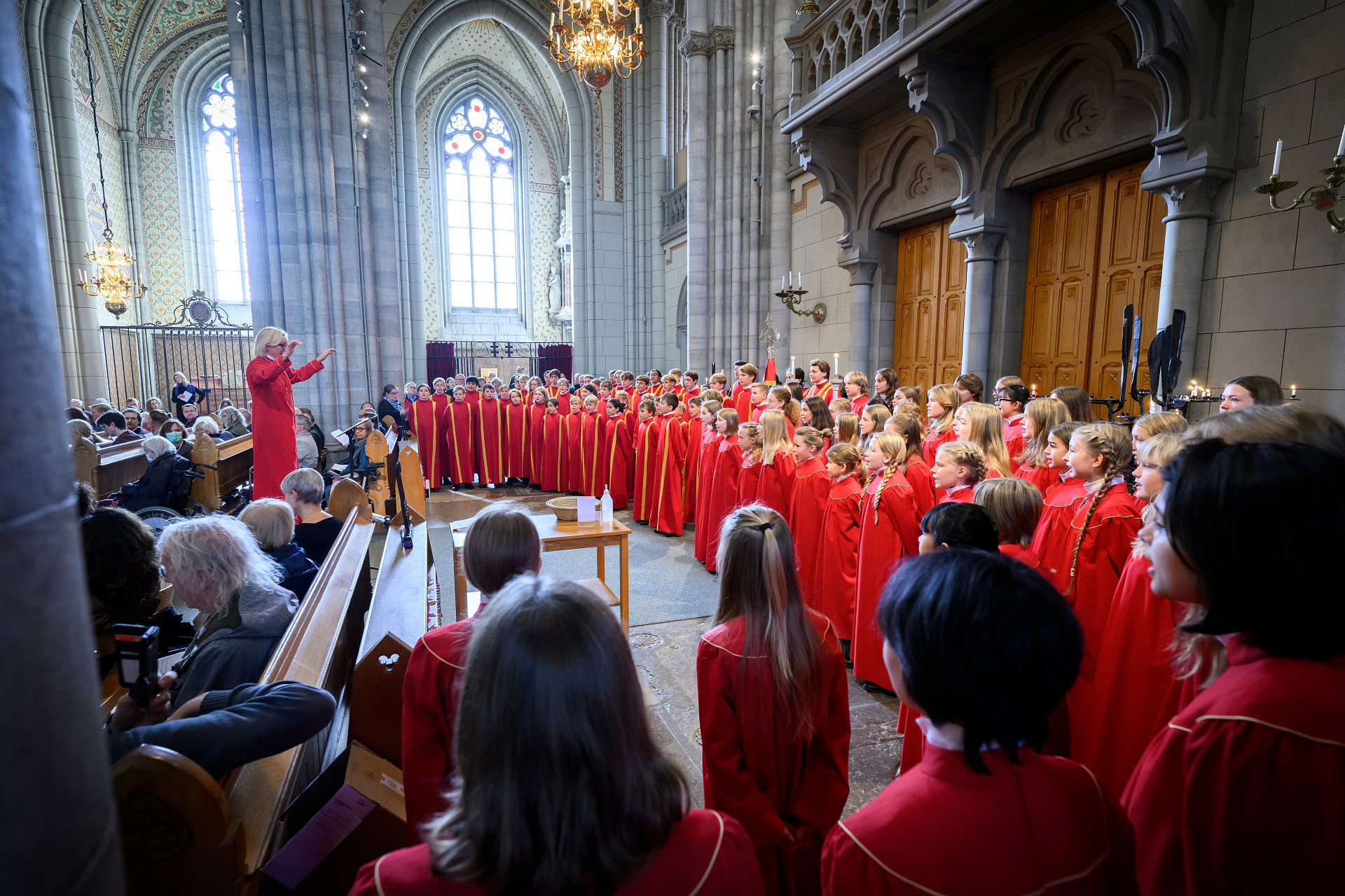 Barn och ungdomar i röda kåpor sjunger i kyrkan.