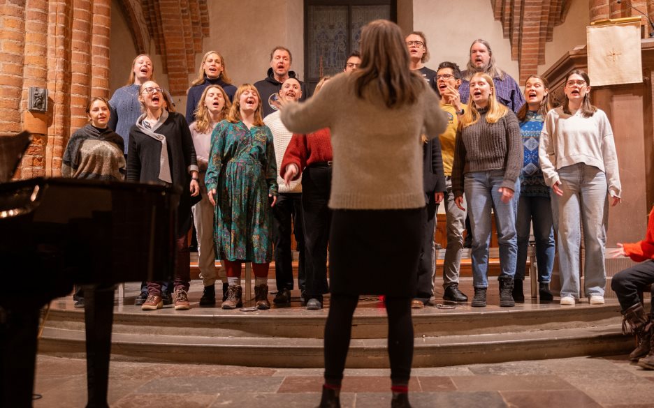 En blandad kör övar i ett kyrkorum.