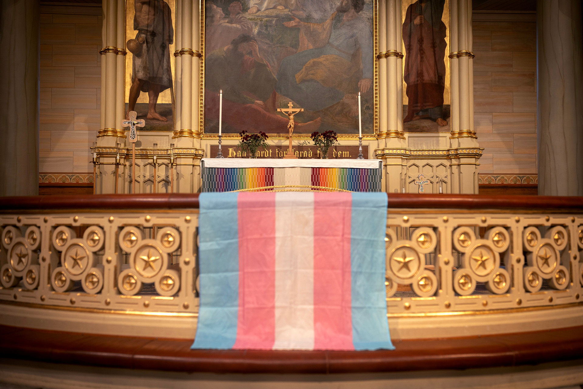 En flagga i rosa, blått och vitt hänger över altaret och representerar transpersoners rättigheter.