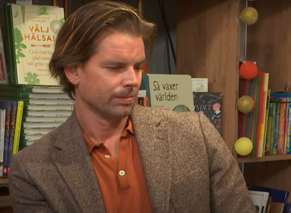 Man sitter i en bokhandel med blicken neråt.