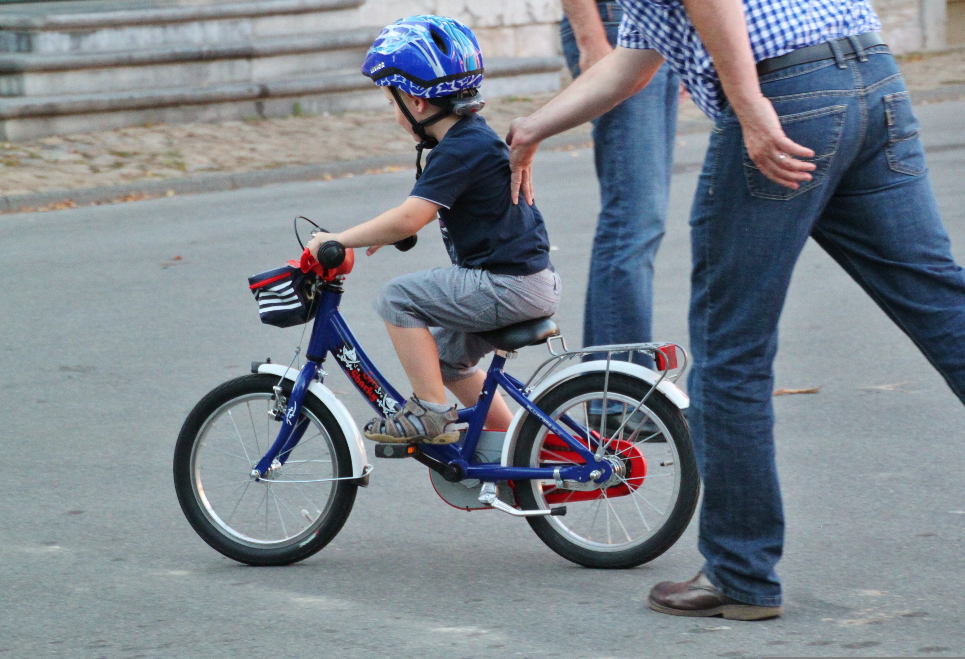 Ett litet barn får hjälp att lära sig cykla.