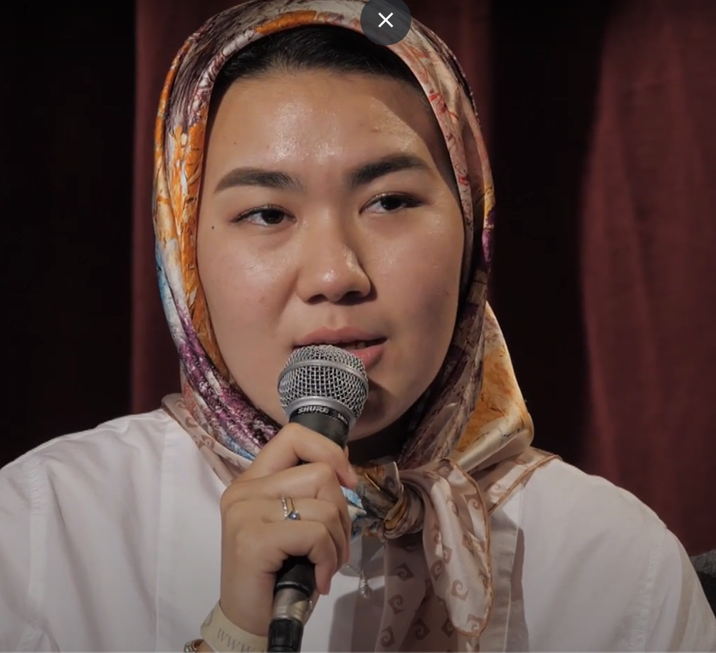 Afganska kvinna med sjal håller mikrofon i handen.