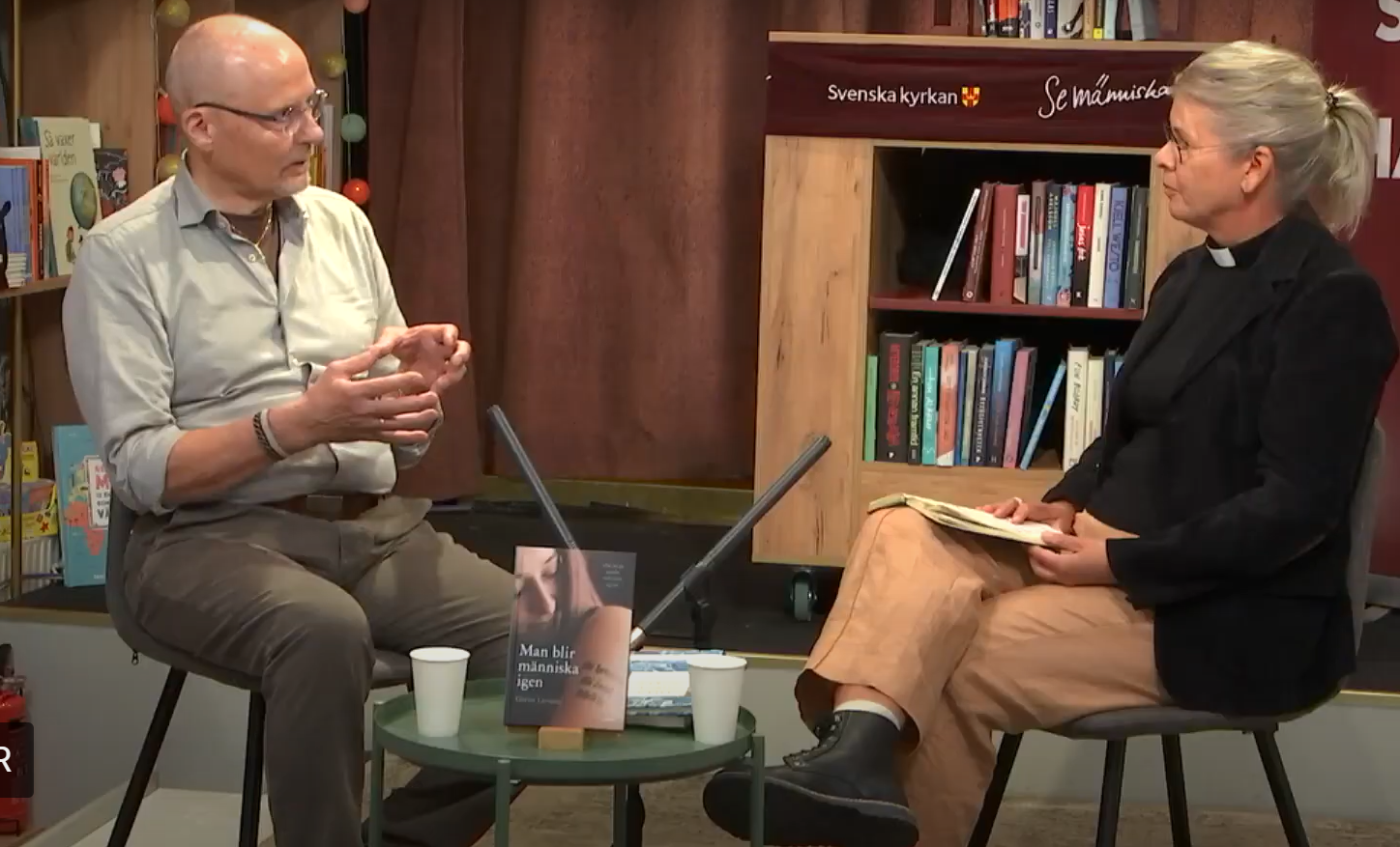 Man och kvinna sitter i en bokhandel och samtalar.