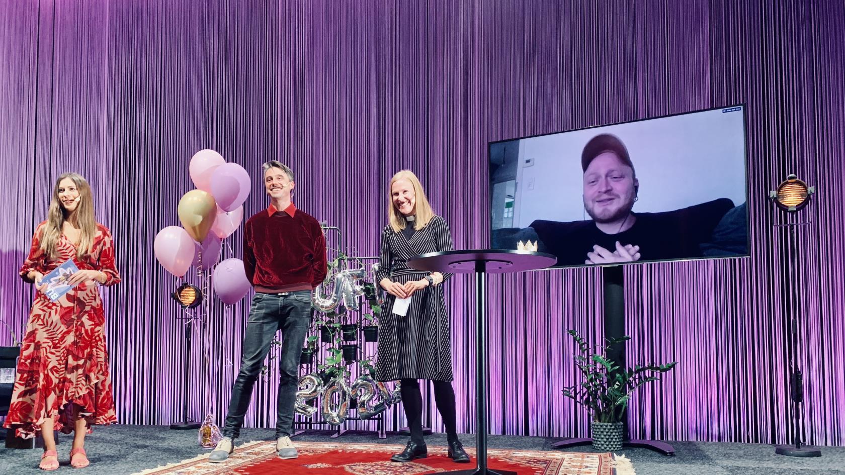 Utdelning på scen av Svenska kyrkans ungdomsfilmspris. På en stor skärm syns vinnaren, Laurent Micheli.