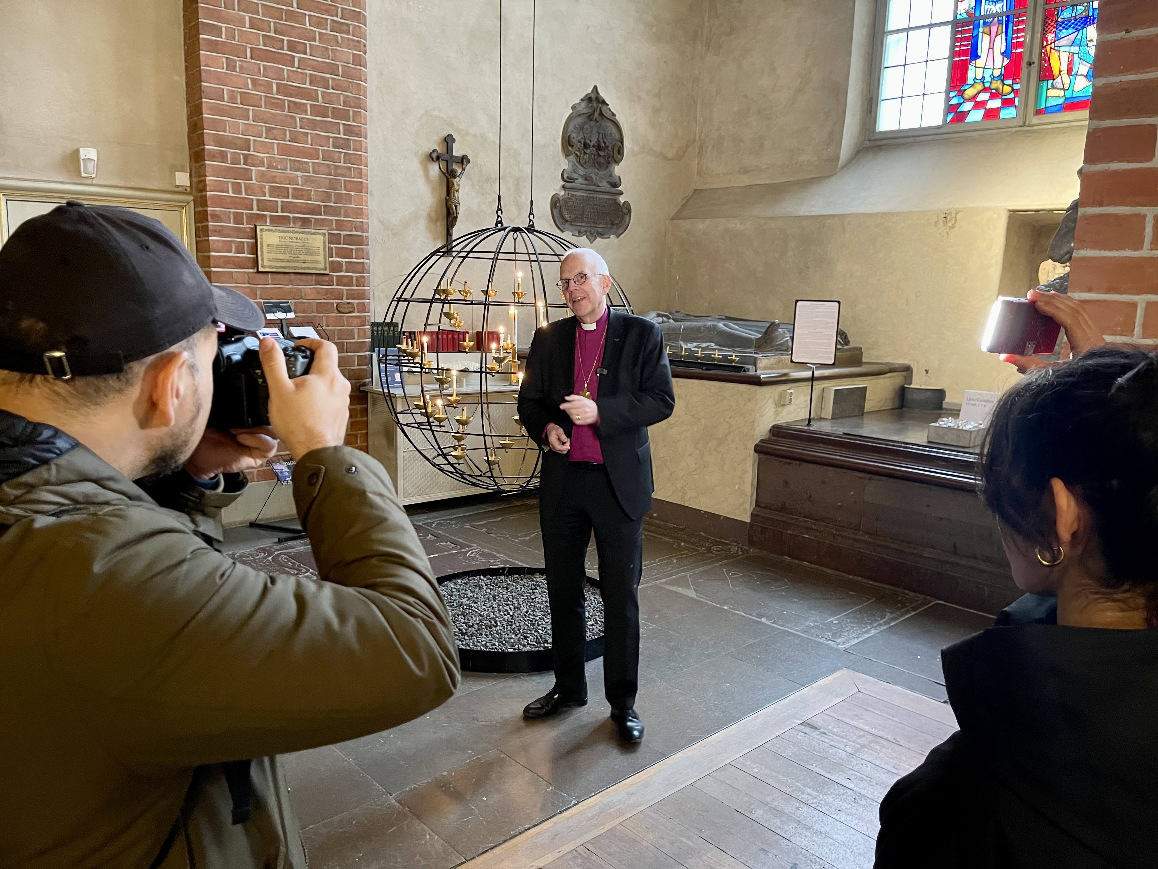 Ärkebiskop Martin Modéus står i en kyrka och blir fotograferad.