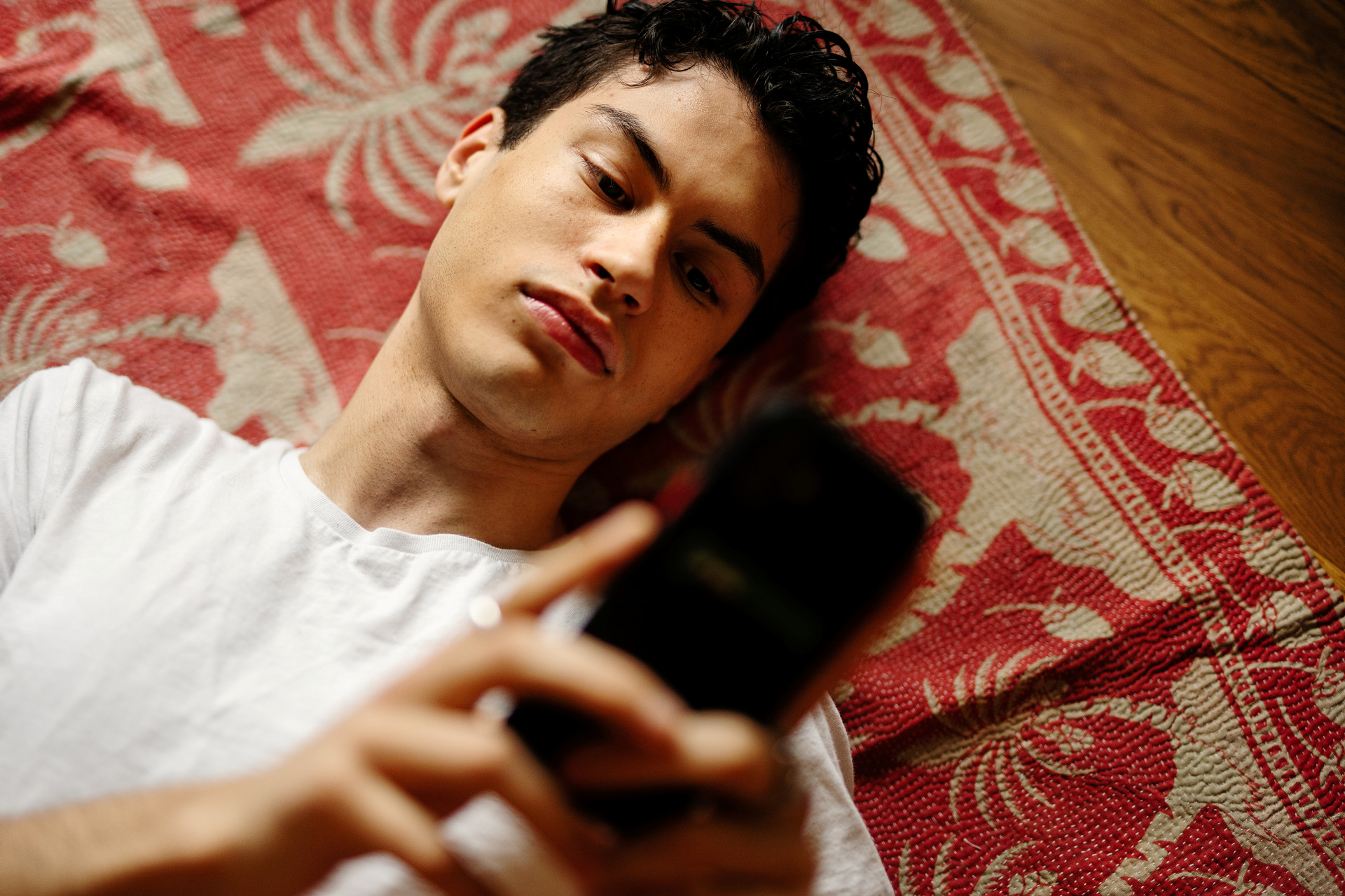 En ung man läser på sin mobil. 