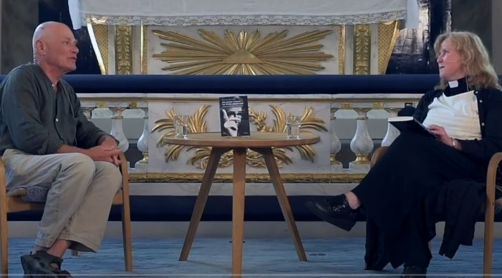 Man och kvinna sitter i en kyrka framför en altare.