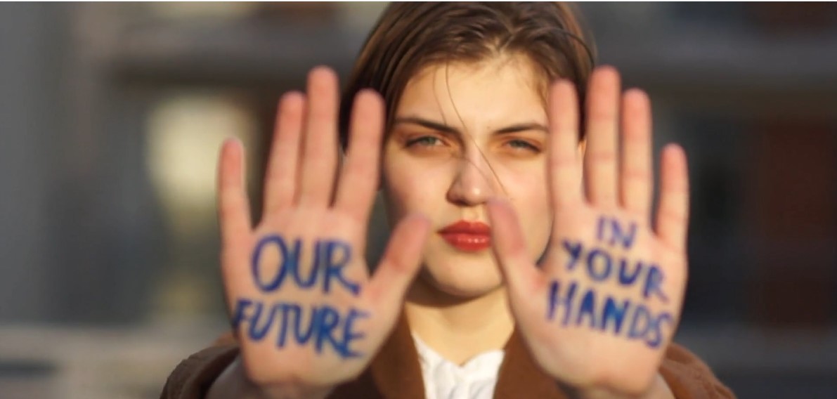 Kvinna håller upp sina handflator mot fotografen, i handflatorna står det: Our future in your hands.