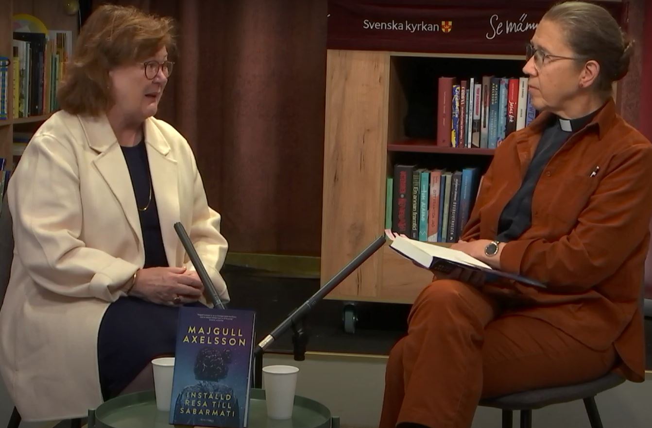 Två kvinnor sitter och samtalar i en bokhandel.