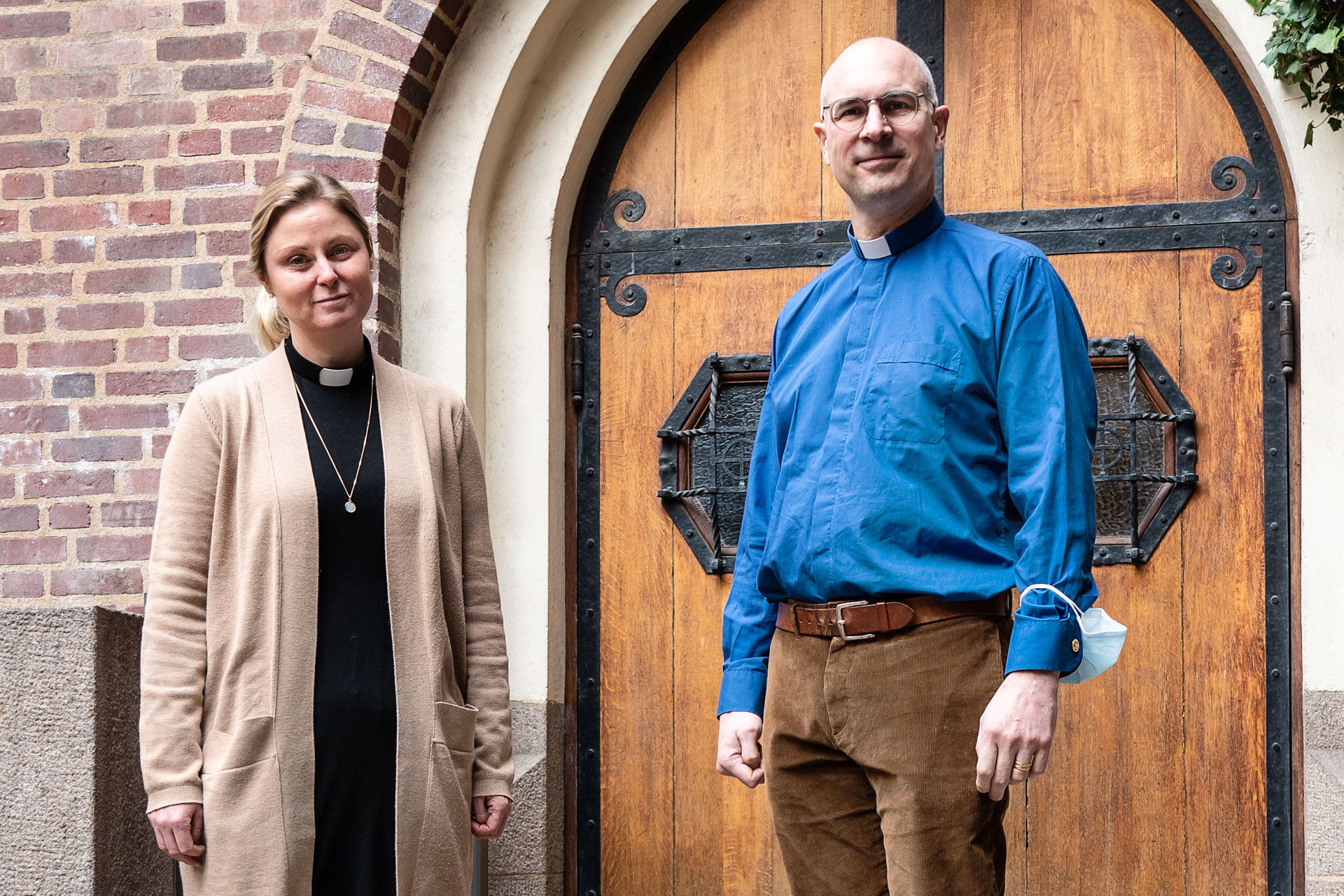 Två personer står framför en kyrkport i trä.