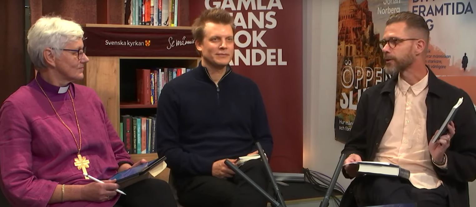 En kvinna och två män sitter och samtalar i en bokhandel.