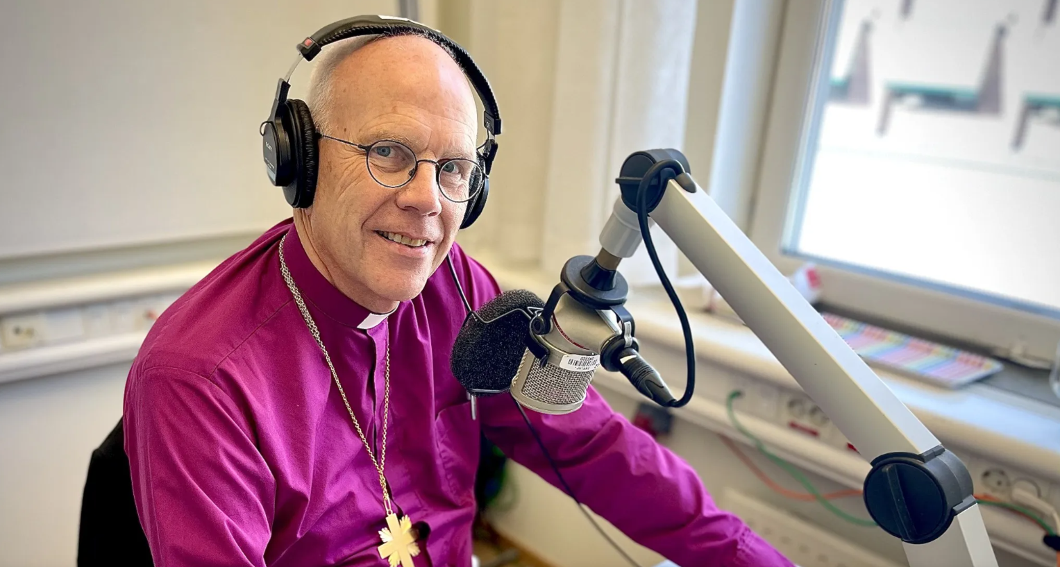 Ärkebiskop Martin Modéus sitter i en studio med hörlurar och pratar i en mikrofon.