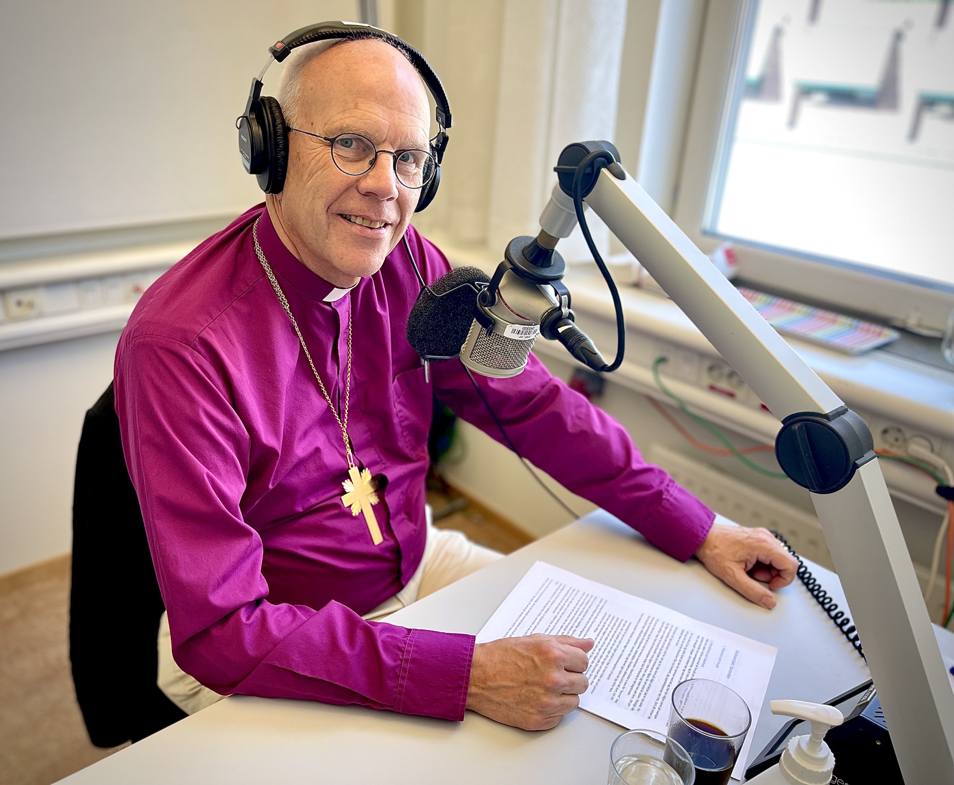 Ärkebiskop Martin Modéus sitter vid ett skrivbord med en radiomikrofon.