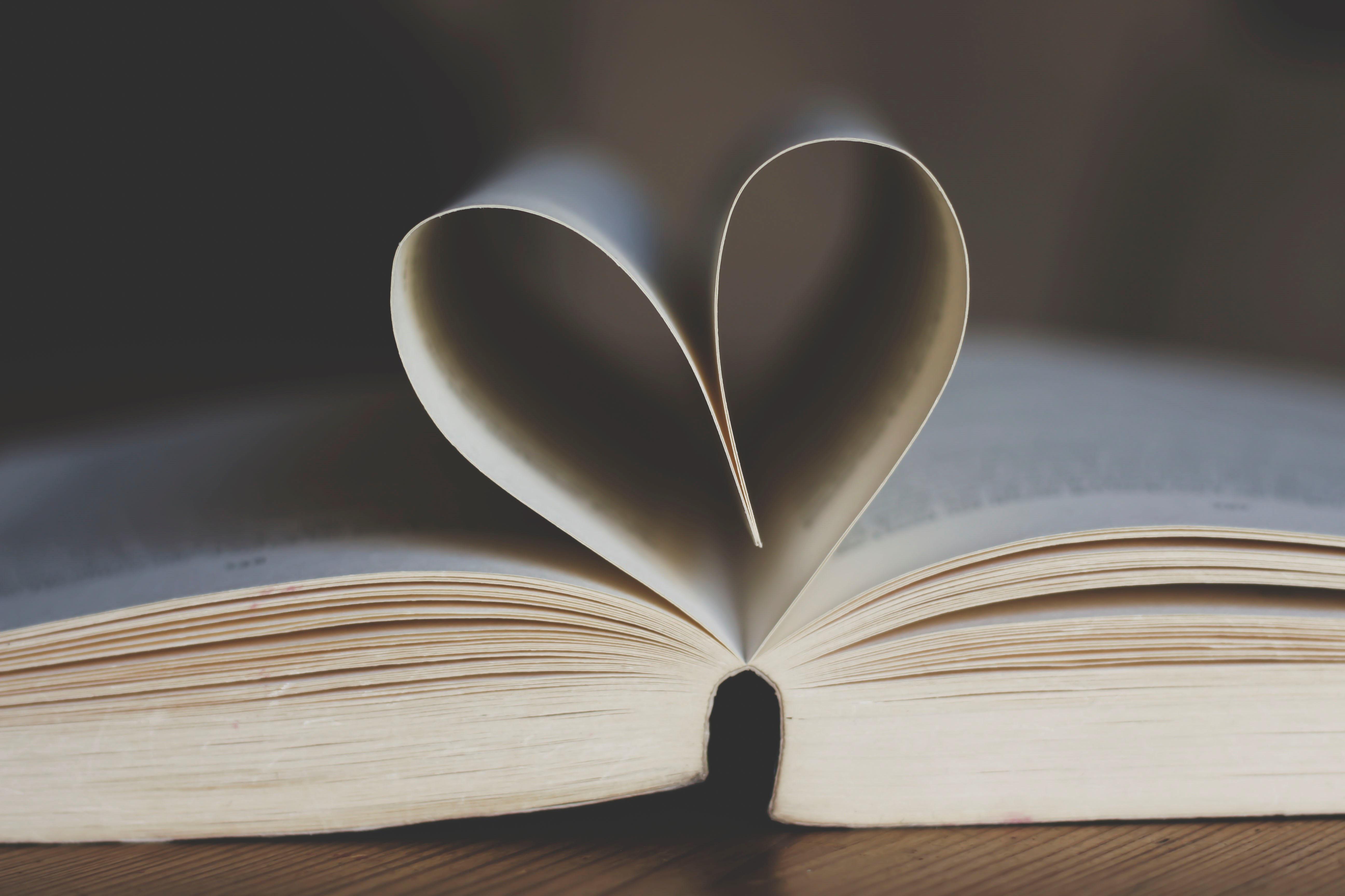 En uppslagen bok där två blad bildar ett hjärta.