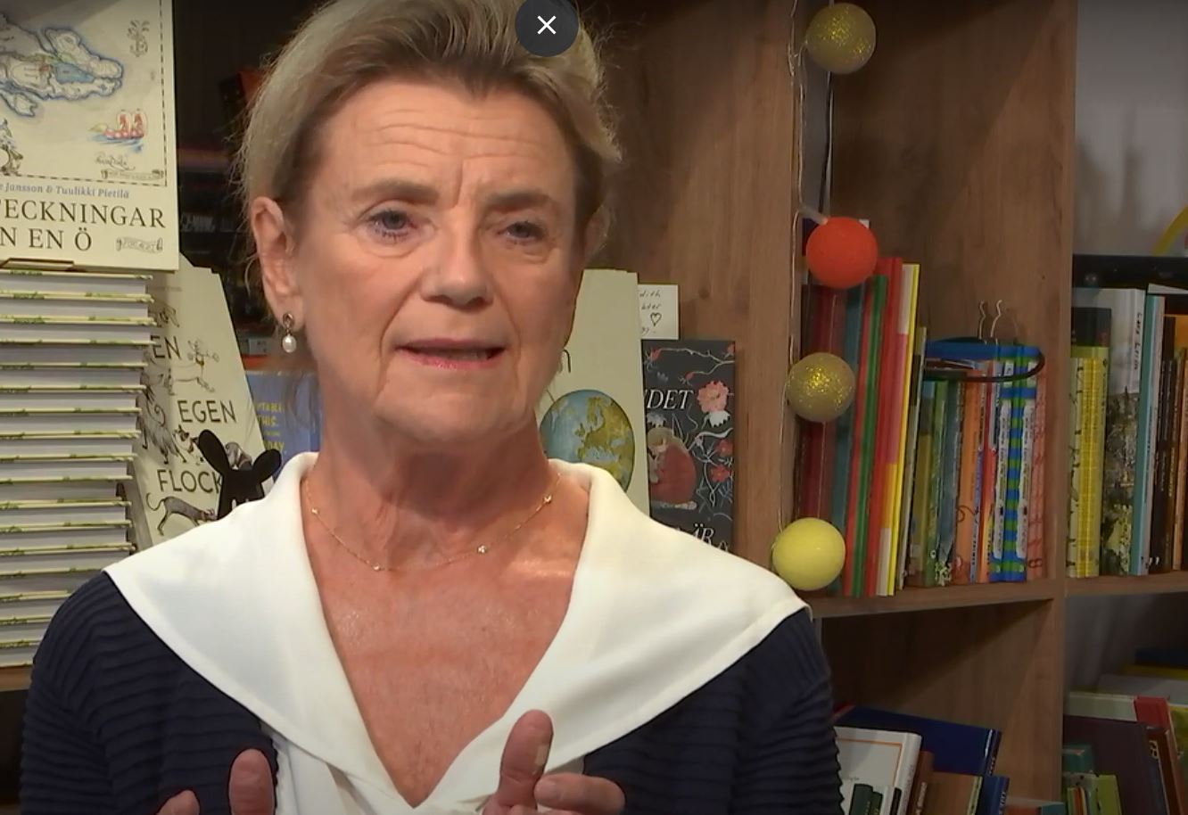 Kvinna småler och gestikulerar med händerna.