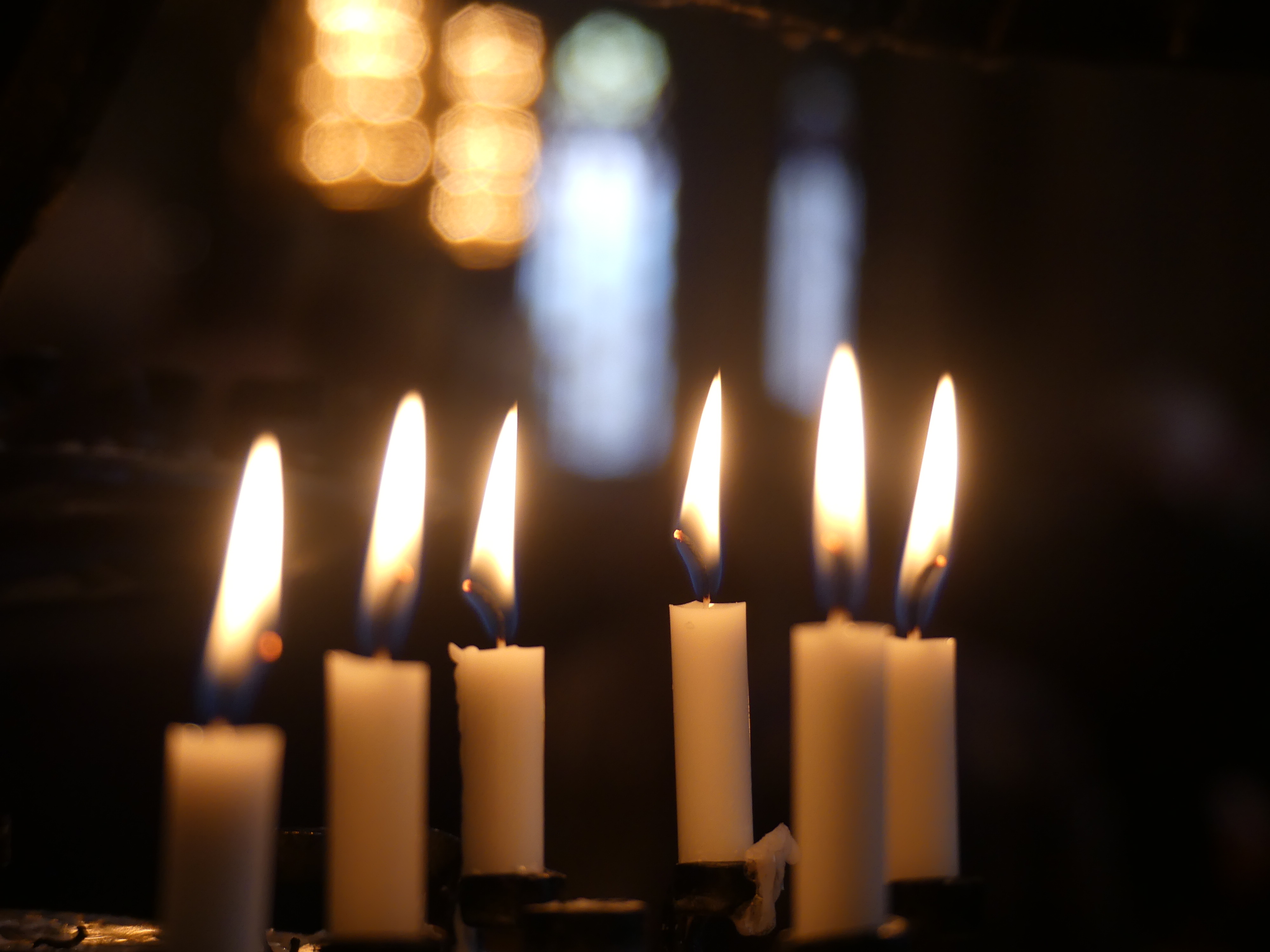 En rad tända vita stearinljus.