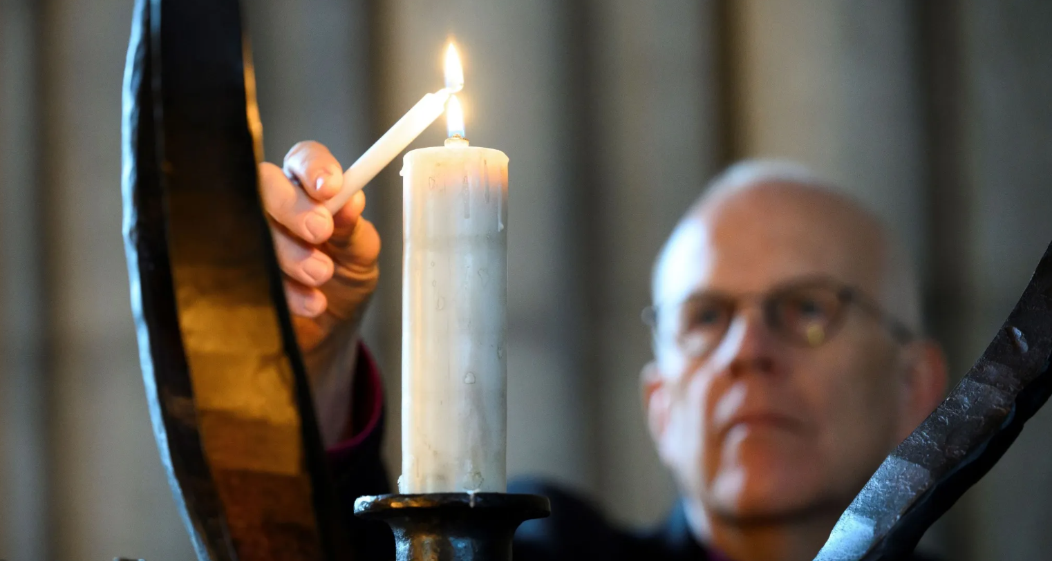 Ärkebiskop Martin Modéus tänder ett ljus i en ljusbärare.