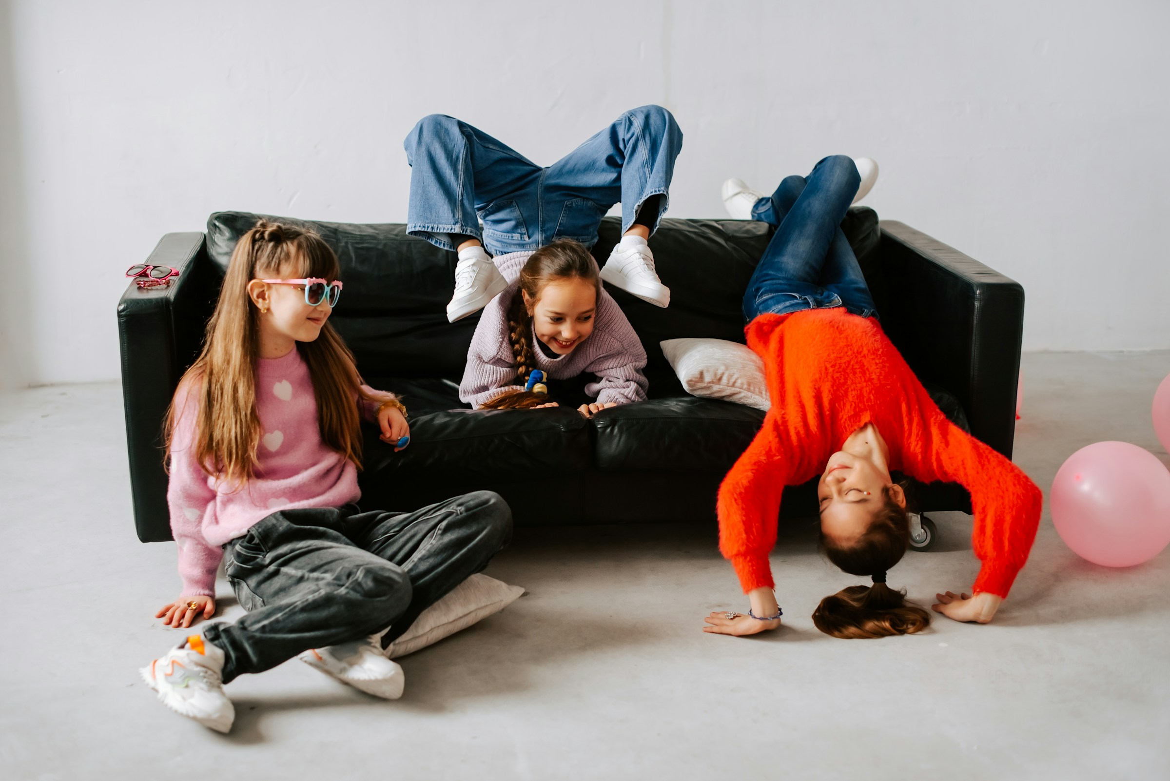 Tre tjejer som utför diverse akrobatik i en soffa