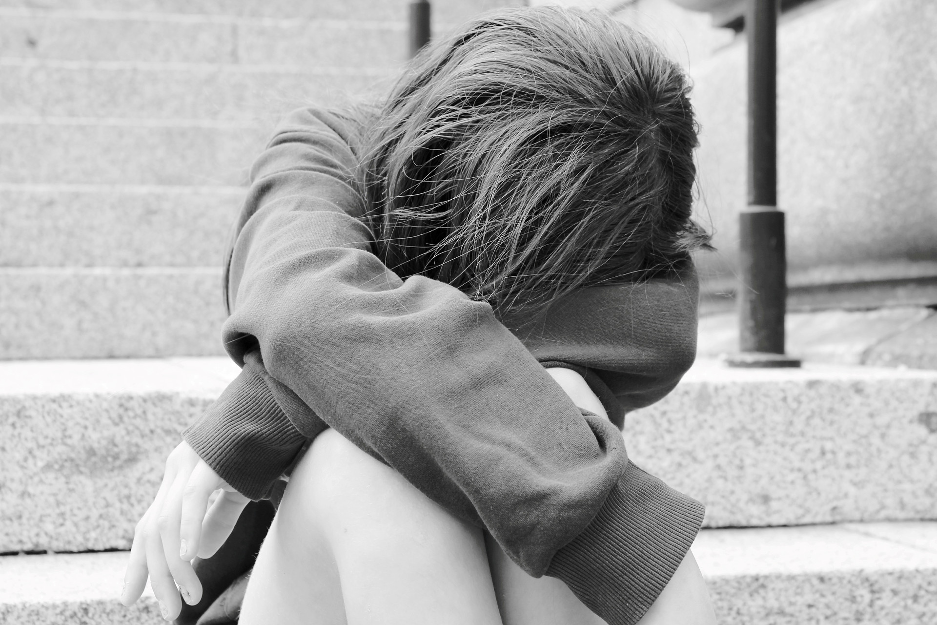Ung person sitter med huvudet nedböjt.