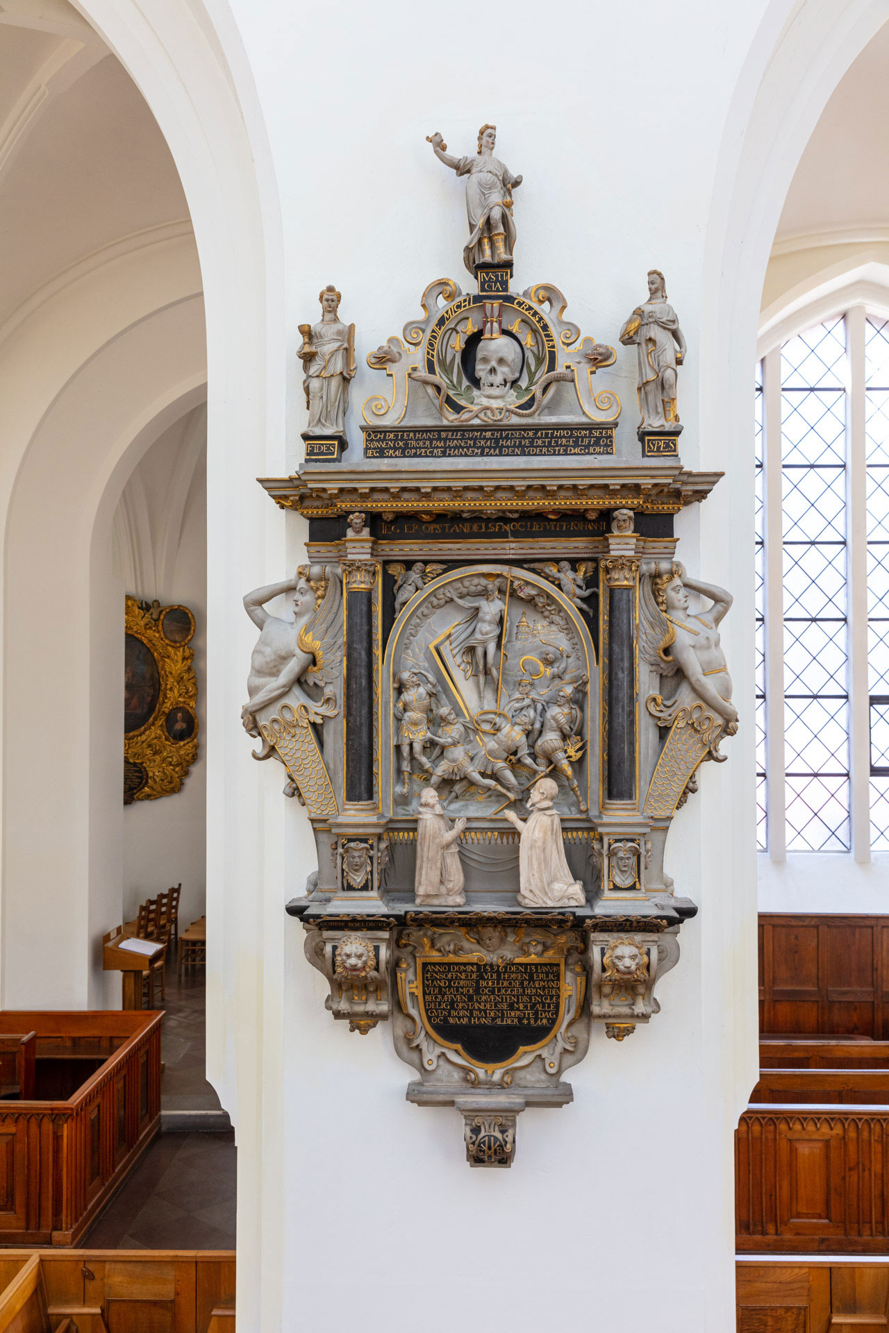 Rikt utformat epitafium i sandsten på en vitkalkad kyrkvägg.