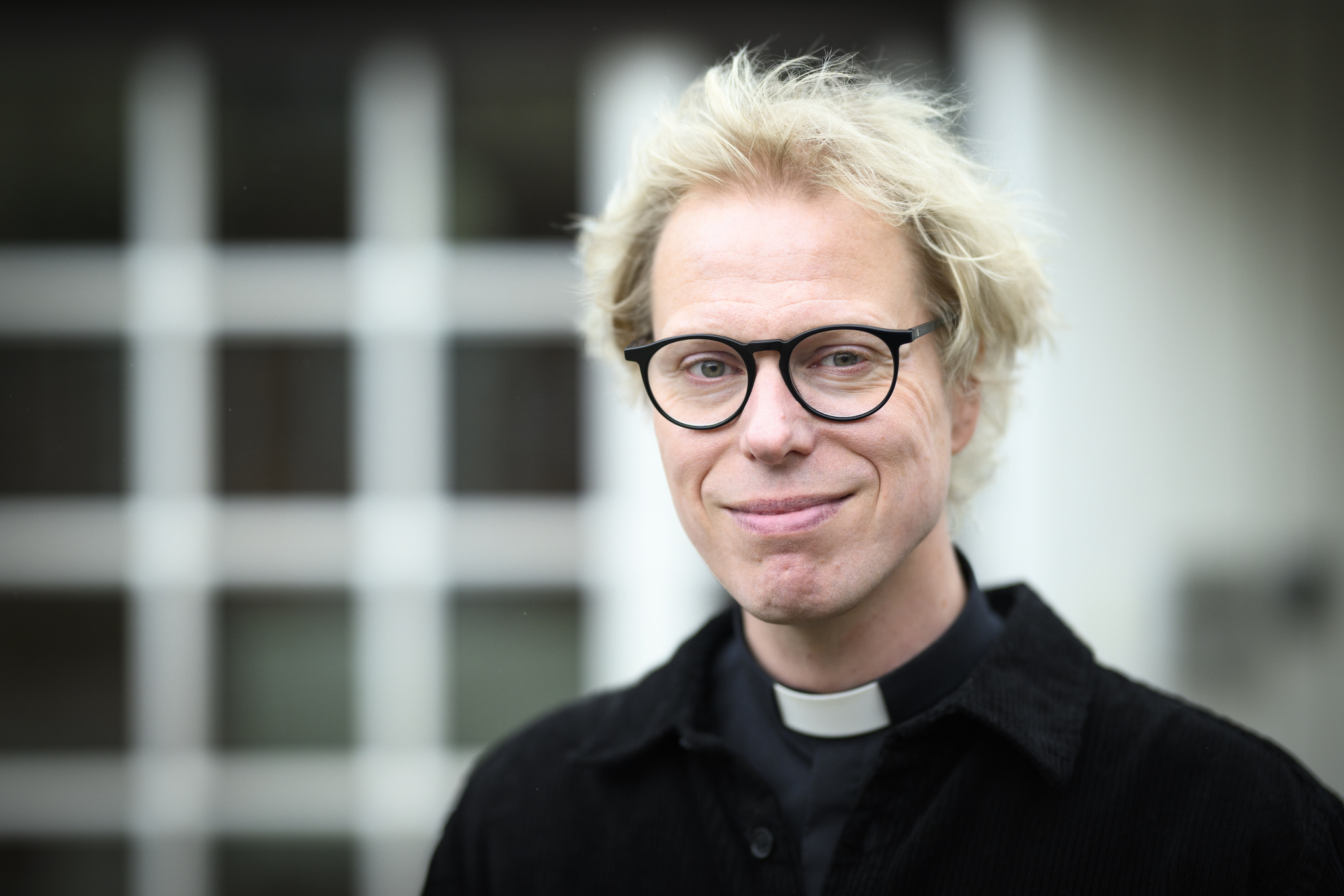 Man med ljust hår och svarta glasögon. Mannen har svart prästskjorta.