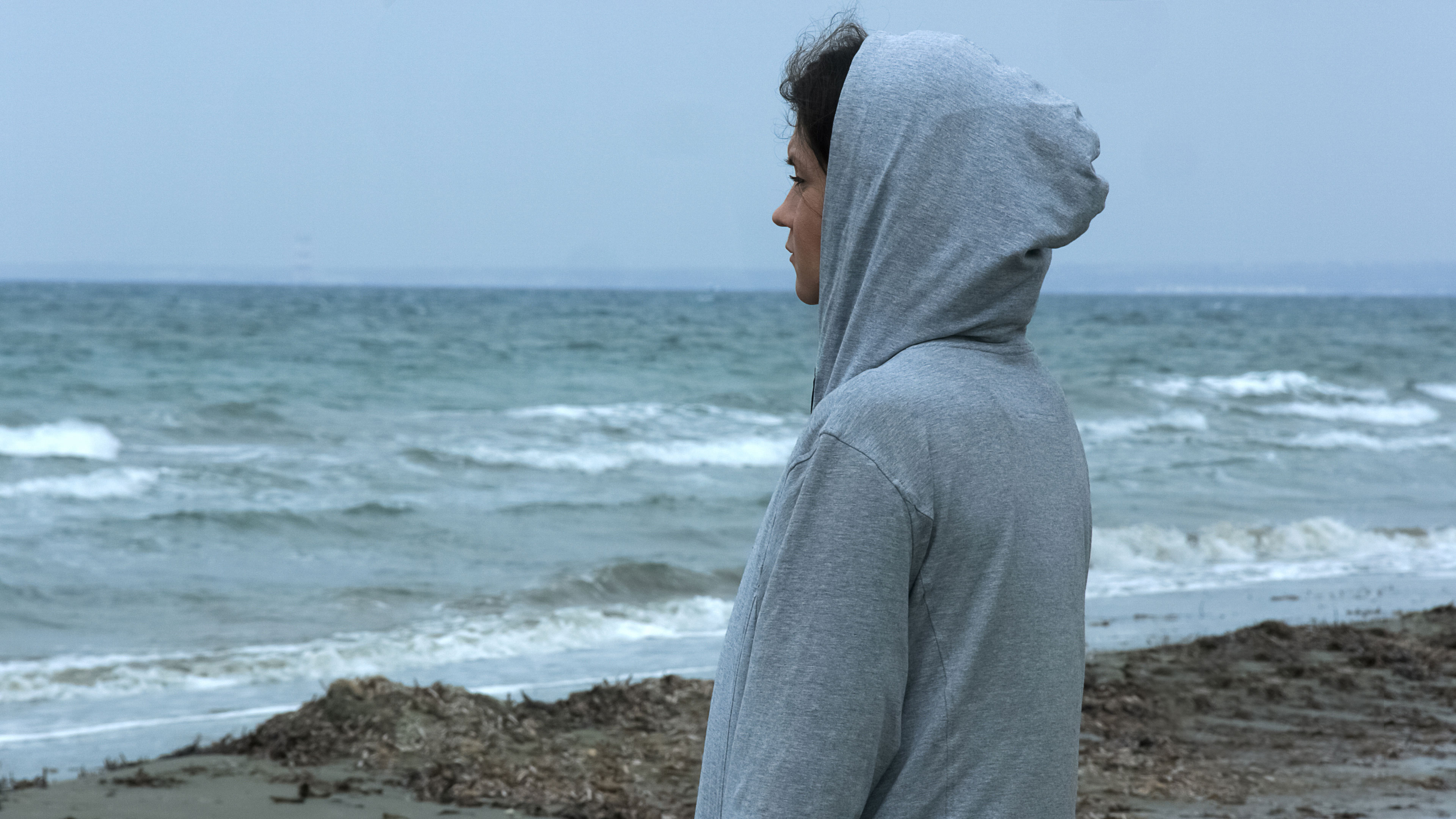 människa i hoodie vid havet