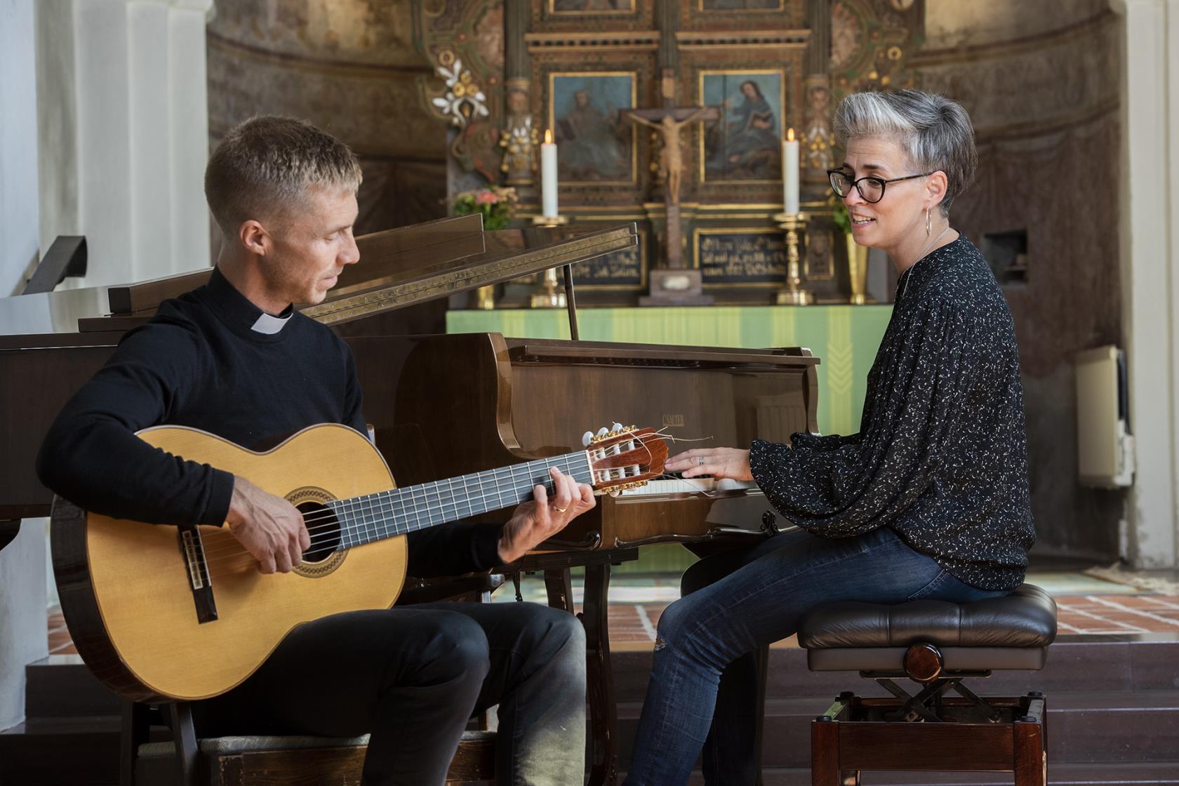 Man med gitarr och kvinna vid piano.