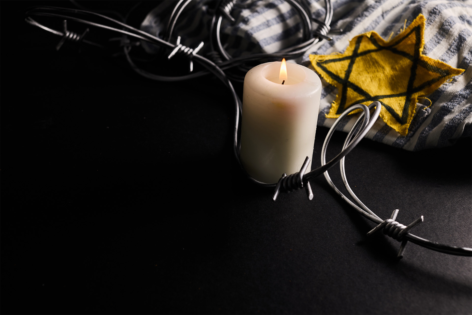 Mörk bild med ett tänt ljus och en Davids stjärna