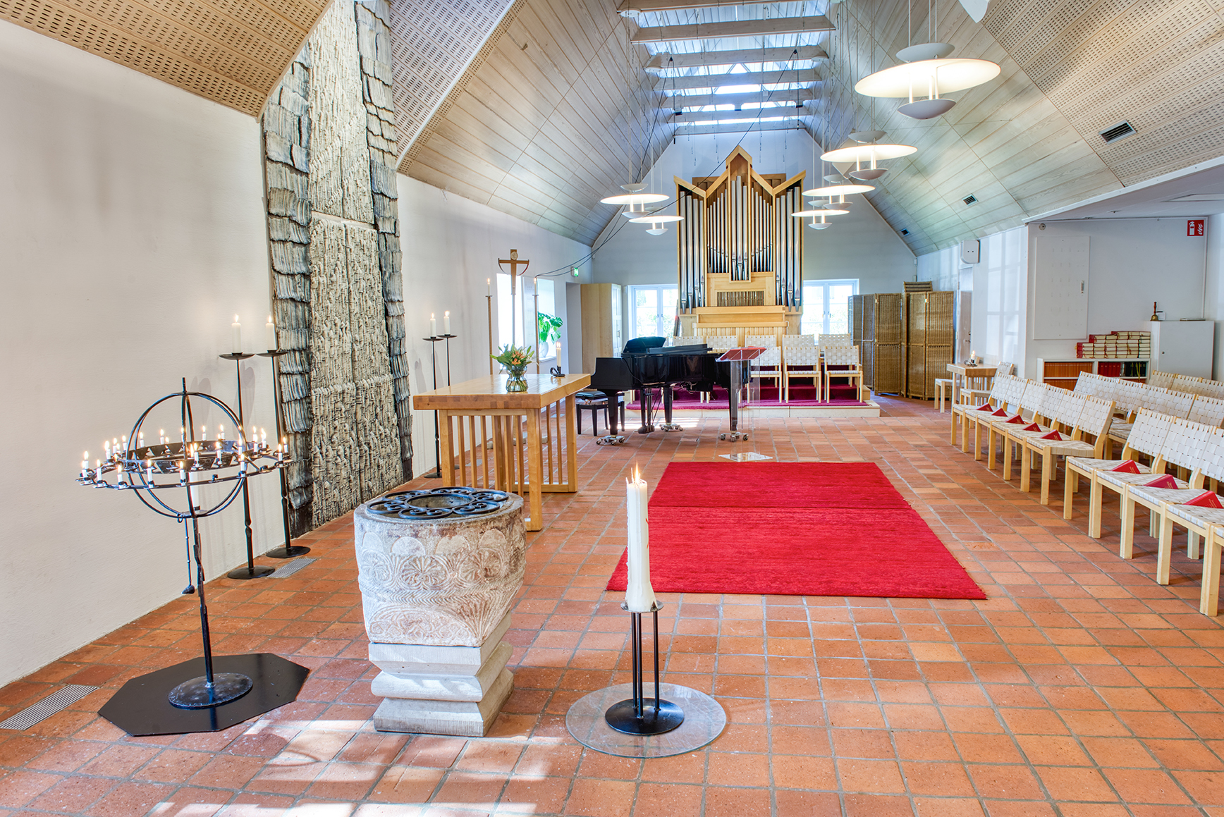 Kyrkorummet med altare, flygel, orgel, ljusbärare och dopfunt i Hyllie kyrka