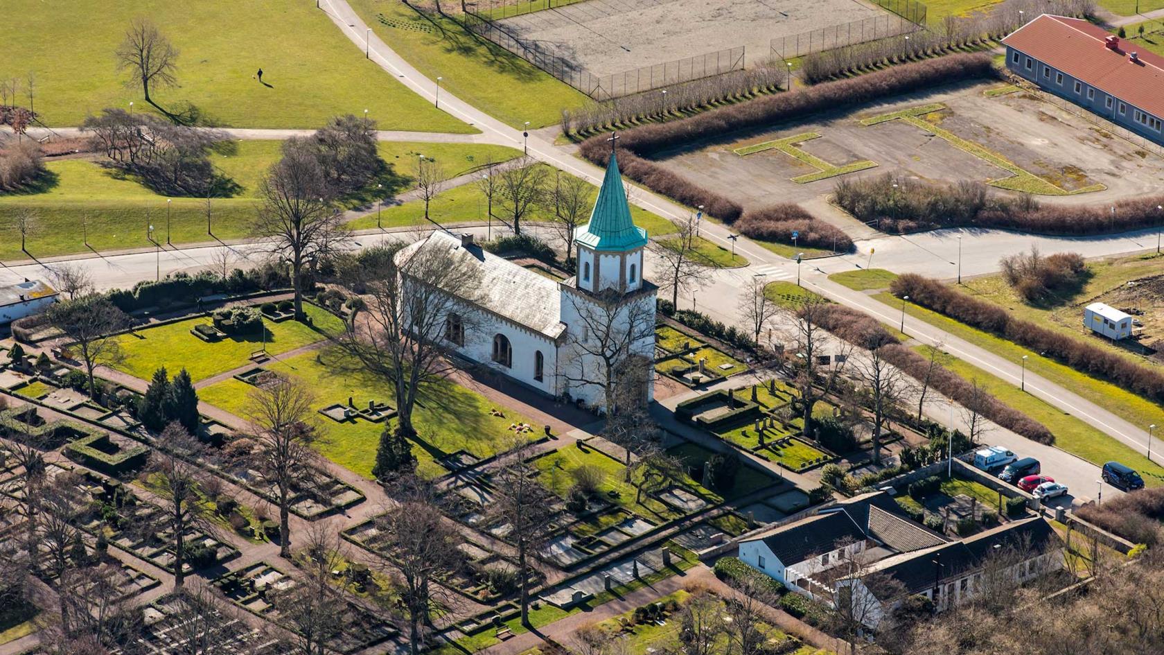Flygfoto över Västra Skrävlinge kyrka i vårljus.