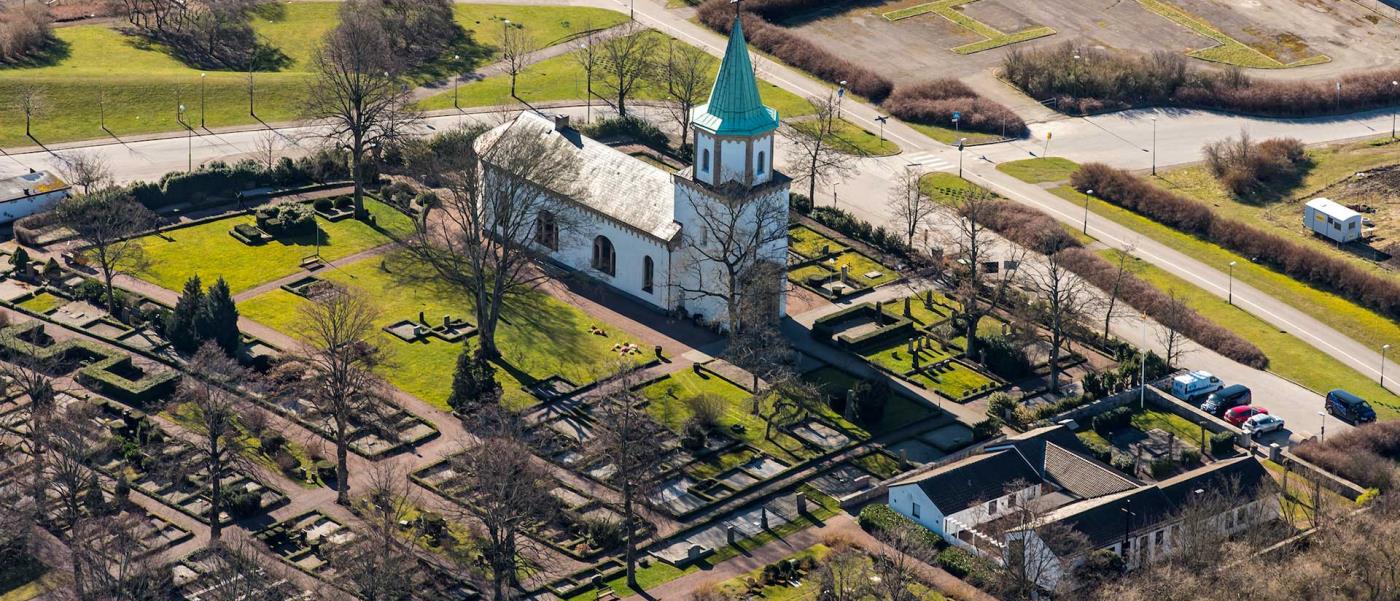 Flygfoto över Västra Skrävlinge kyrka i vårljus.