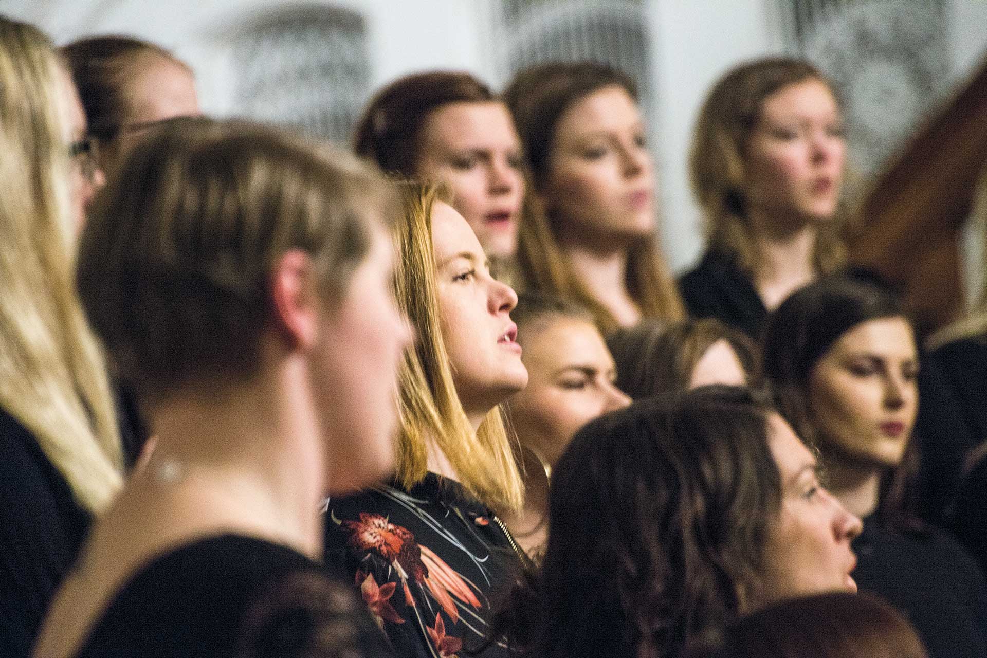Närbild på kvinnliga unga körsångare i kyrkorummet.