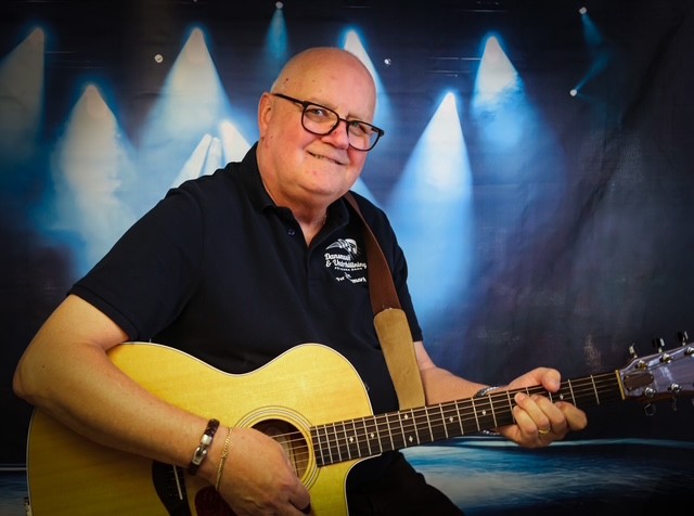Man med glasögon och gitarr