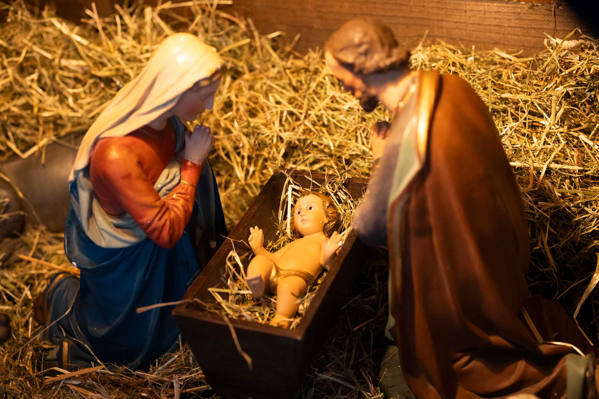 Figurer som föreställer Maria och Josef på knä på var sin sida om barnet i krubban.