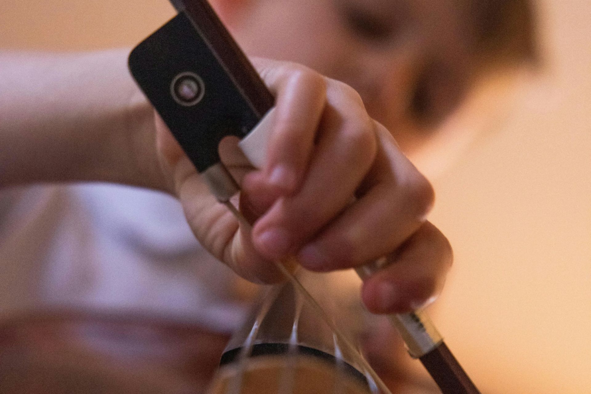 Närbild  på en hand som spelar ett stråkinstrument.