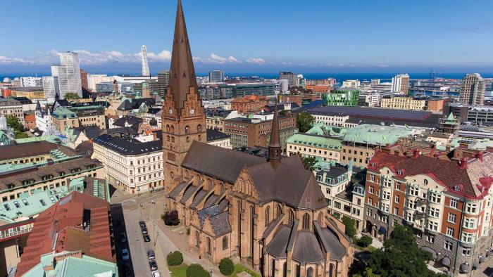 Flygbild över S:t Petri kyrka under en klarblå himmel och med Turning Torso i bakgrunden.