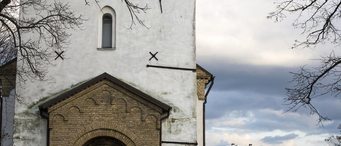 Ingång till kyrka med höghus i bakgrunden