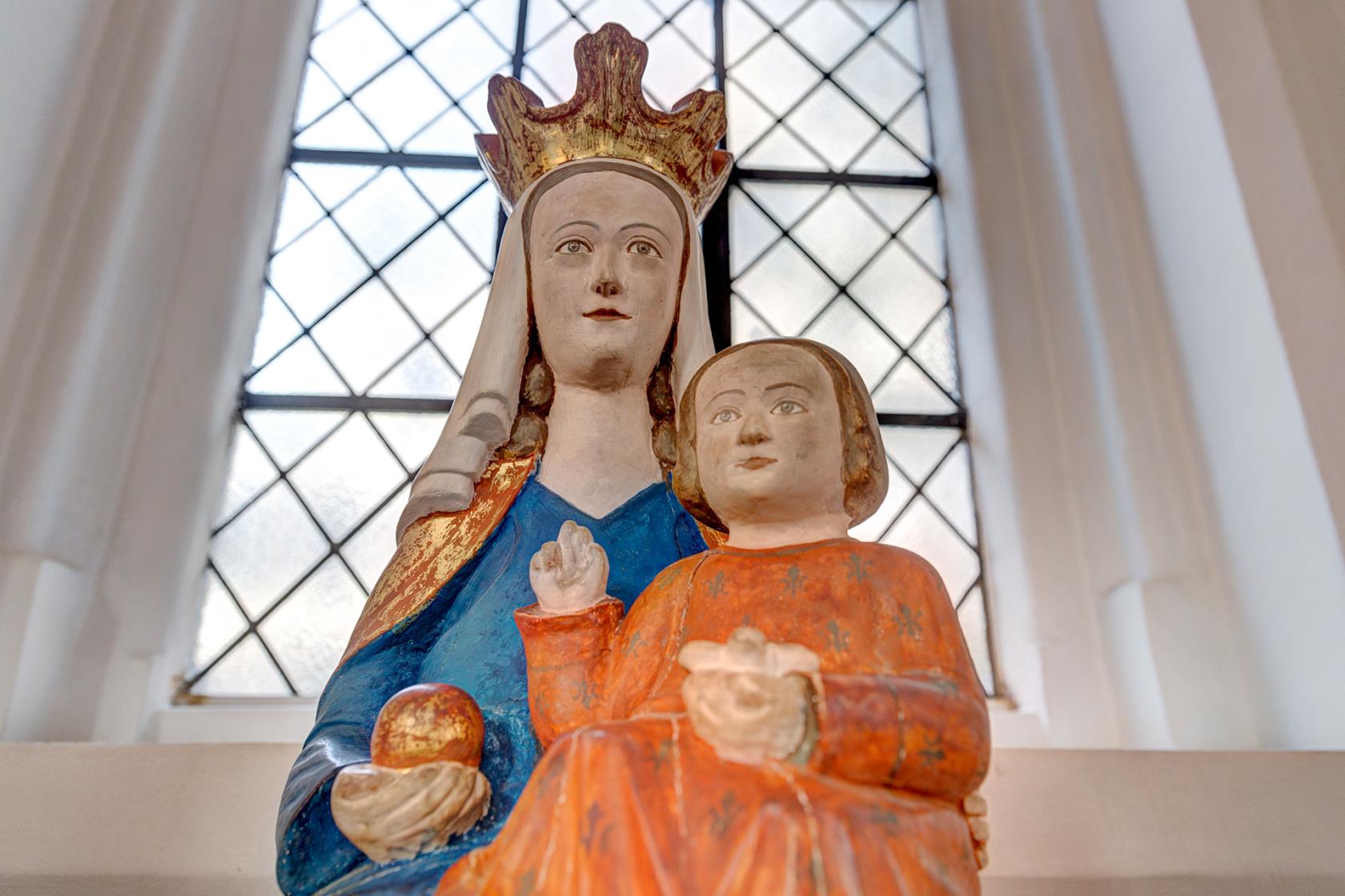 Staty i trä av jungfru Maria med Jesusbarnet i famnen och ett guldäpple i handen.