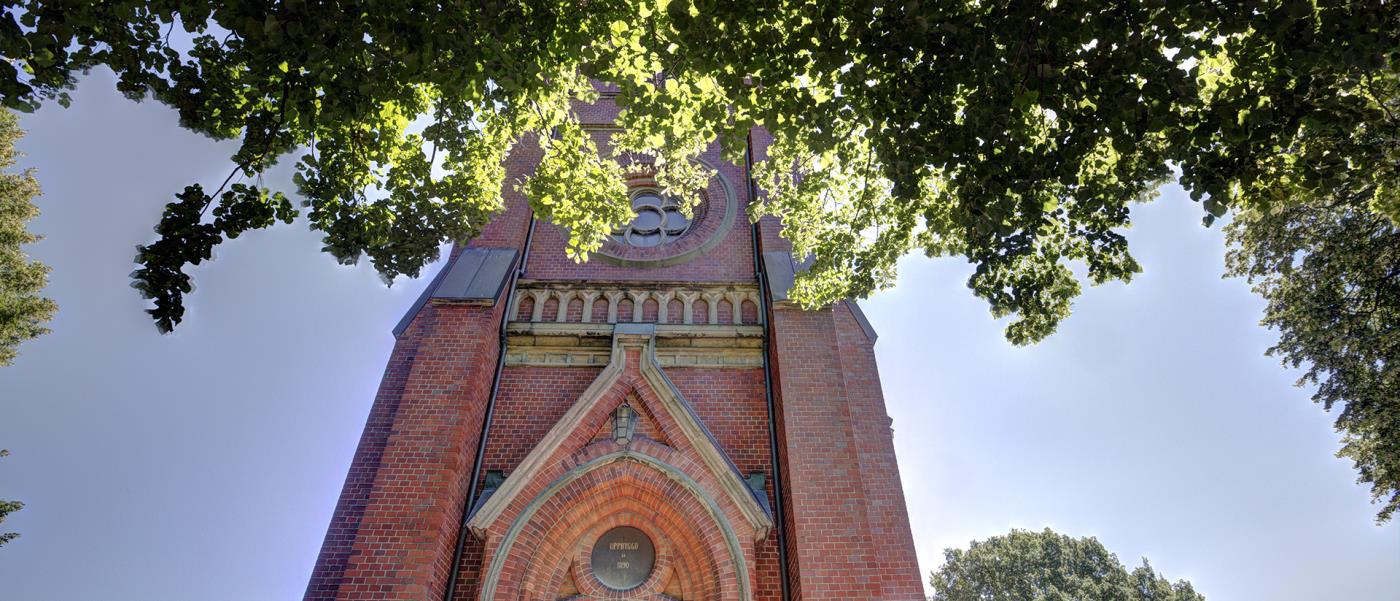 Träd i förgrunden och kyrktorn i bakgrunden