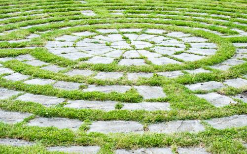Grå betongplattor i gräsmattan i form av en labyrint med labyrintens centrum.