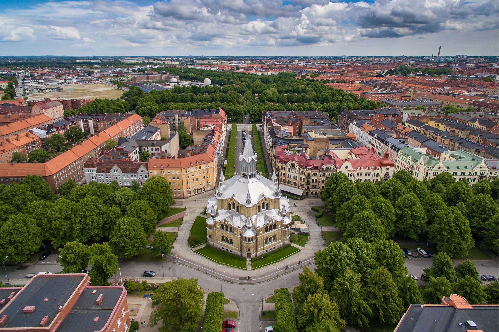 Fotografiet är taget snett från ovan där S:t Pauli kyrka med tolv små och ett stort torn i silverglänsande aluminium blänker. Kungsgatan med grönskande trädallé löper vågrätt och lodrätt hitom ligger Hjalmar Gullbergsgatan och bortom ligger Sankt Paulli kyrkogata.  