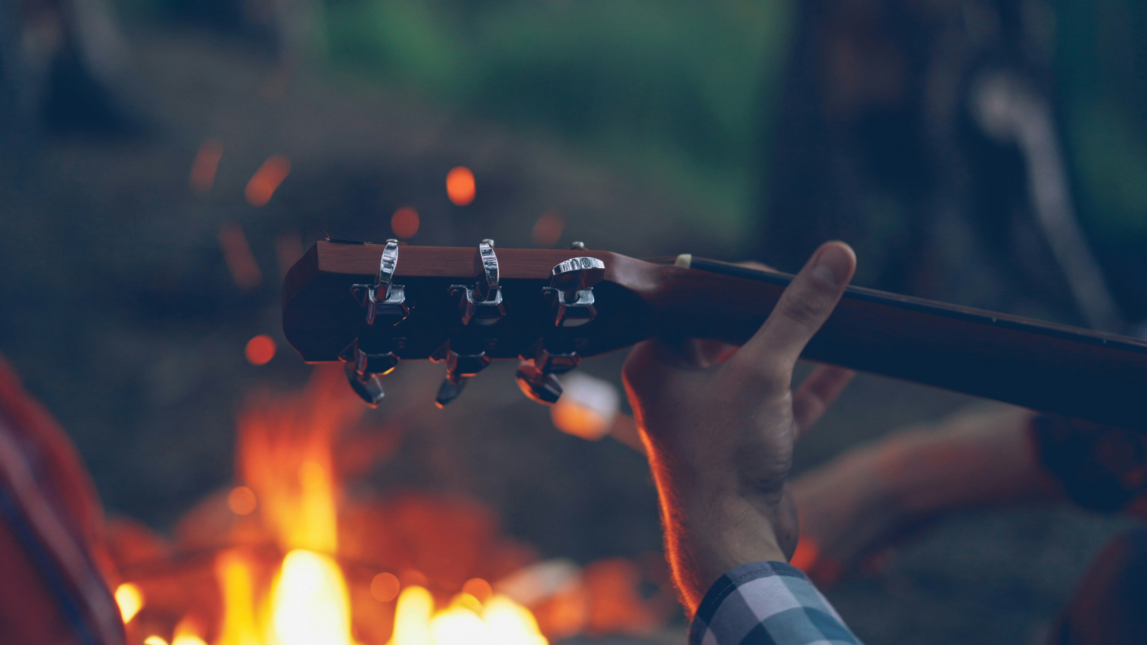 Hand som håller i gitarr med eld i bakgrunden